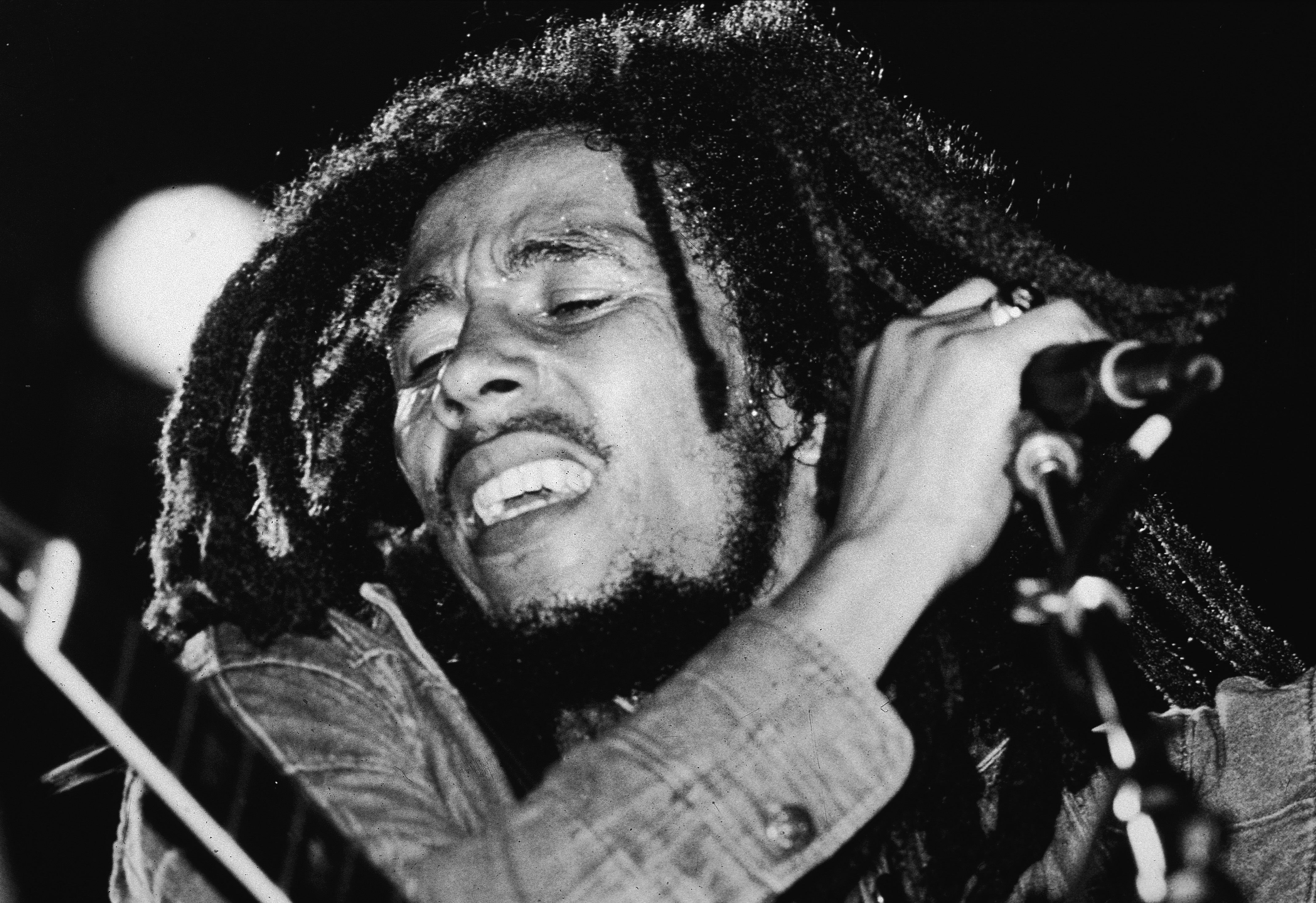 Jamaican reggae musician Bob Marley (1945 - 1981) performs on stage, a microphone in his hand, late 1970s. (Photo by Expre...
