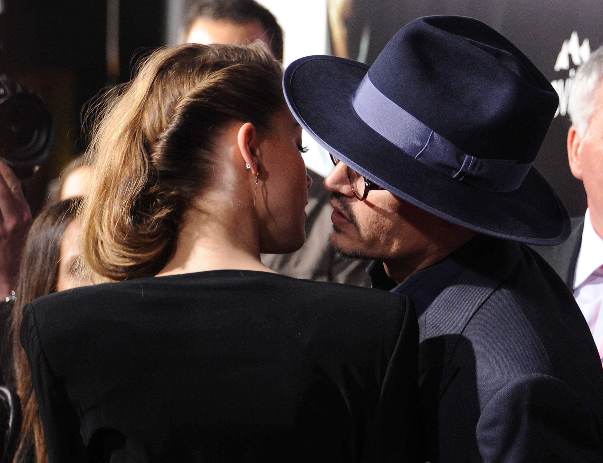 Actor Johnny Depp  (R) leans over to kiss actress Amber Heard (L) as they attend the US premiere of "3 Days To Kill," at A...