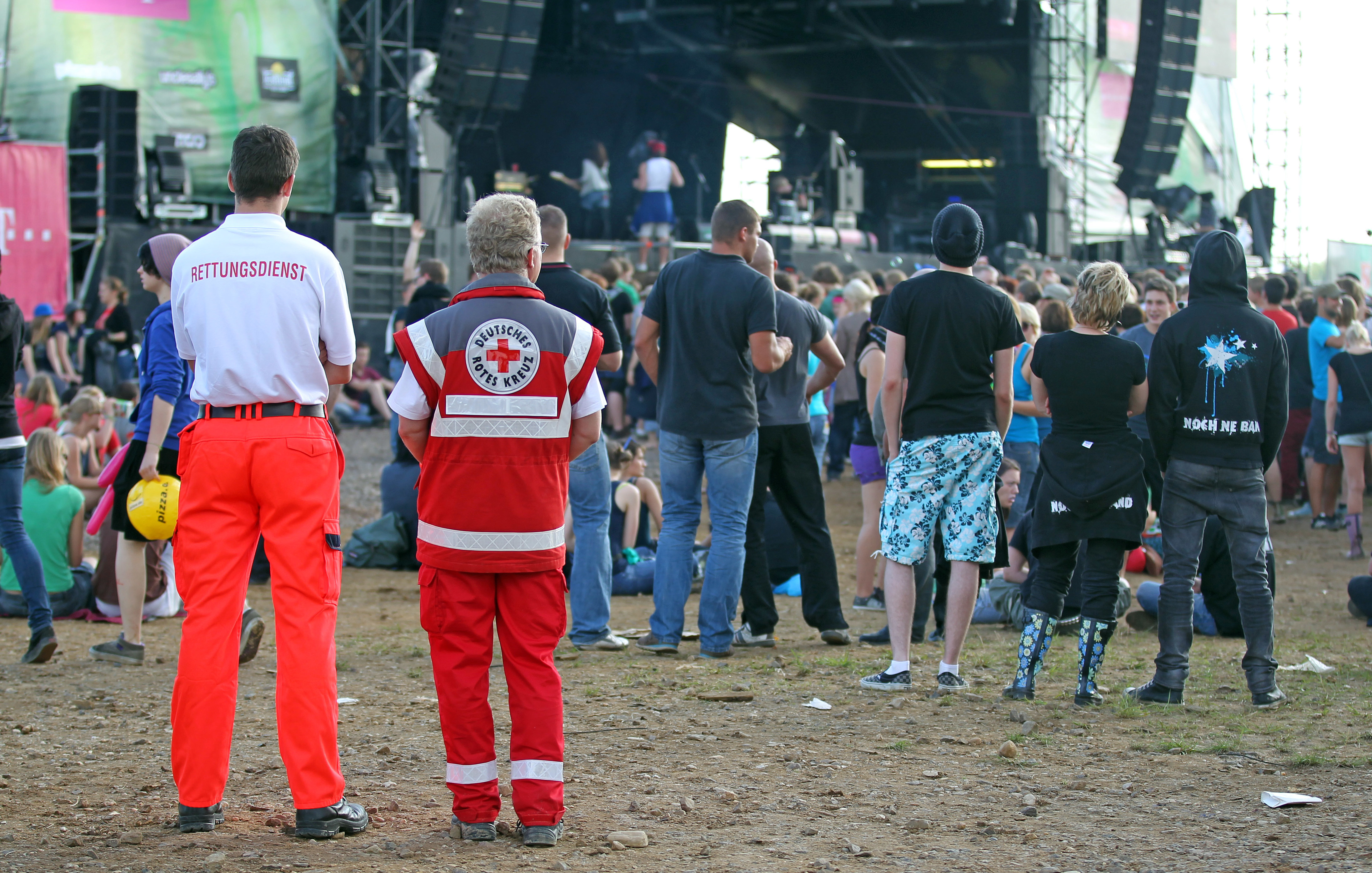 Ein Sanitäter und ein Notarzt stehen hinter Festival-Besuchern