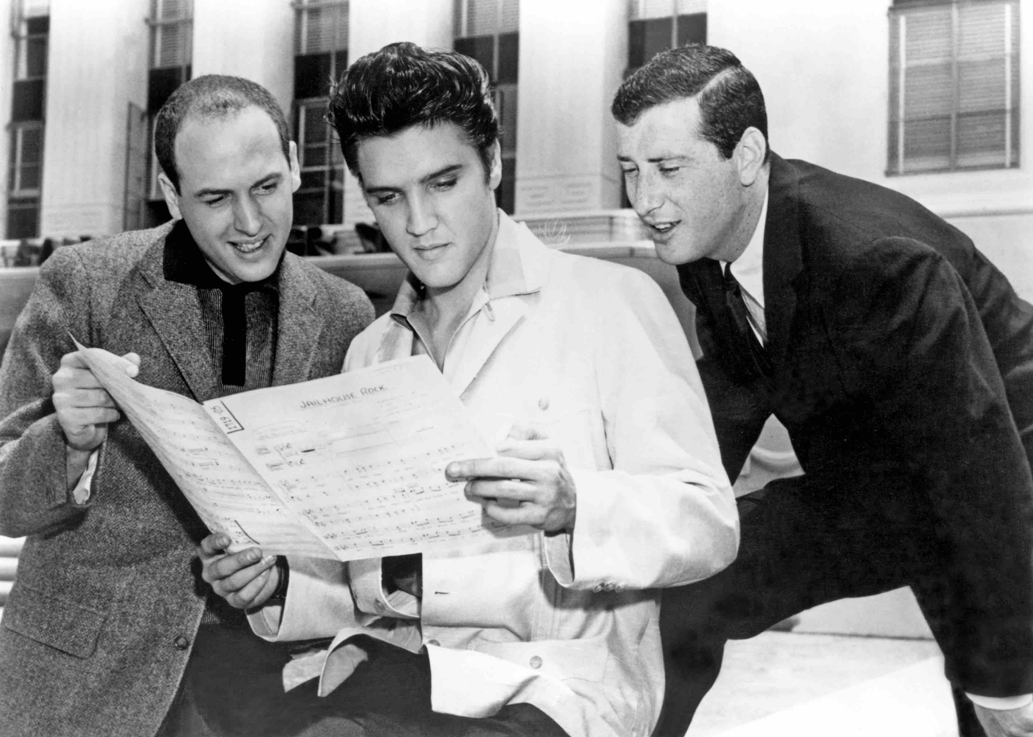 CULVER CITY, CA - 1957:  Rock and roll singer Elvis Presley with songwriters Leiber and Stoller looking over the sheet mus...