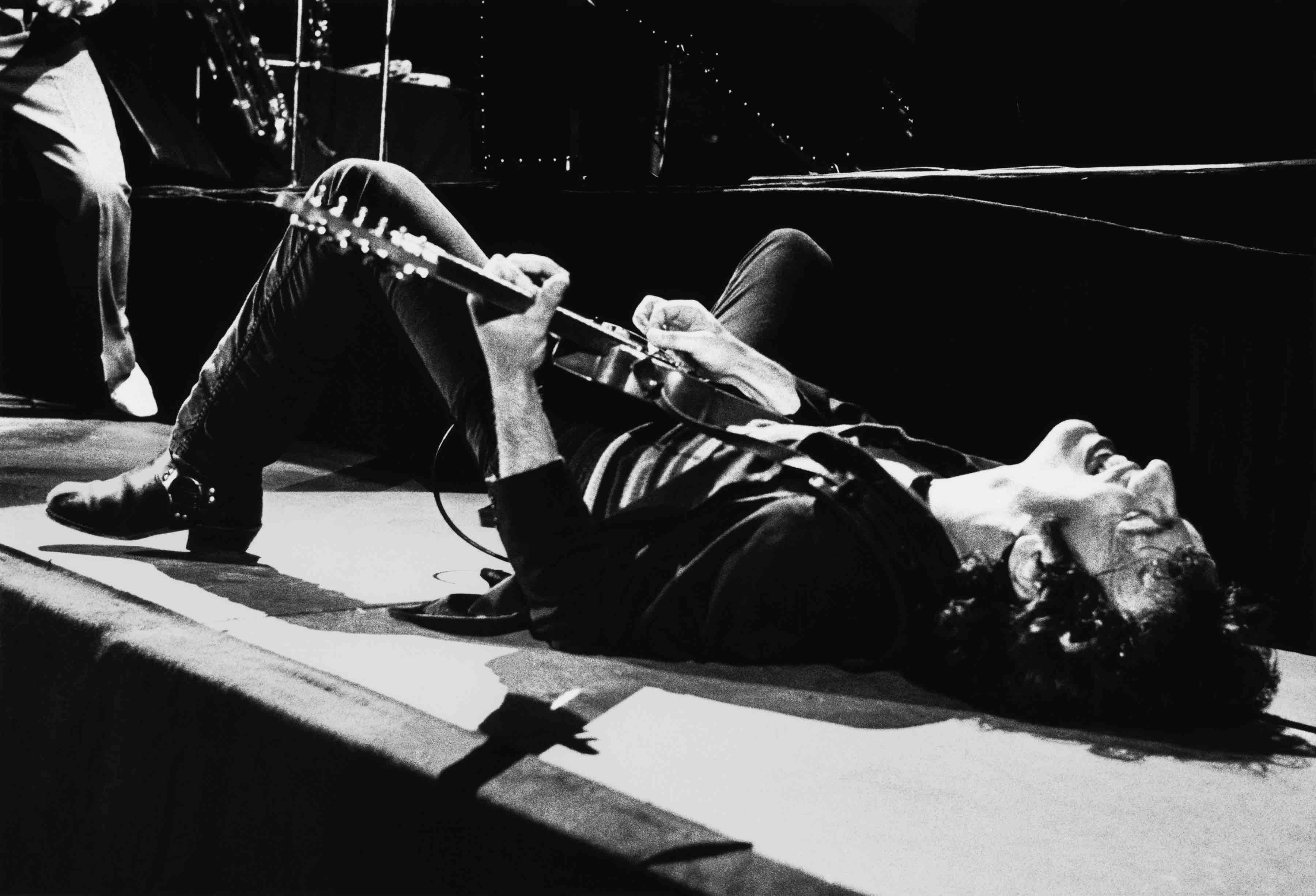 LOS ANGELES, CA - 1979:  Rock and roll icon Bruce Springsteen falls to the stage and continues playing the guitar on his b...