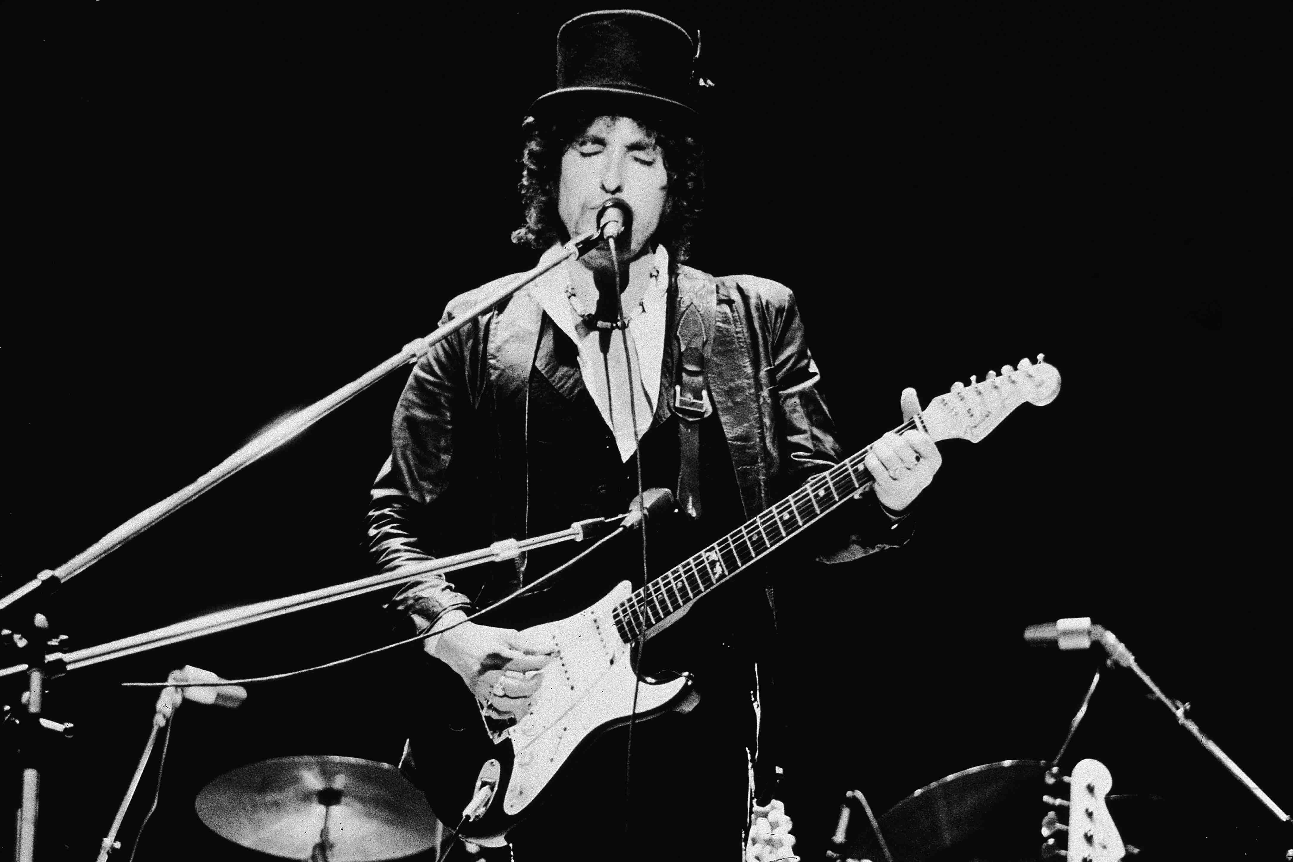 American singer and songwriter Bob Dylan sings and plays guitar on stage, wearing a top hat, during the Blackbushe Pop Fes...
