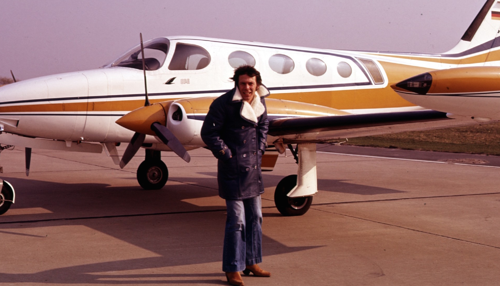 Reinhard Mey am Flughafen neben einem Flugzeug