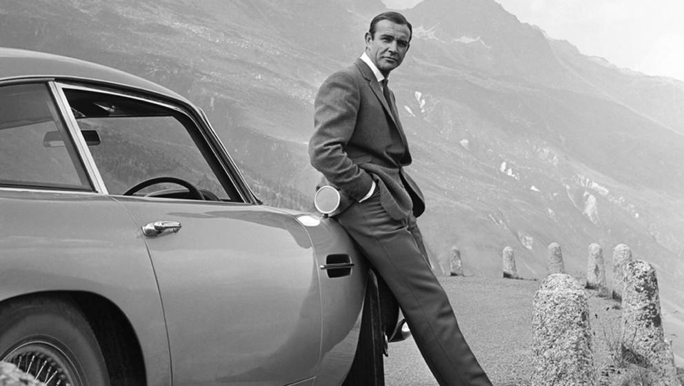 1964: Bond-Darsteller Sean Connery posiert mit dem legendären Aston Martin DB5 am Set von „Goldfinger“.