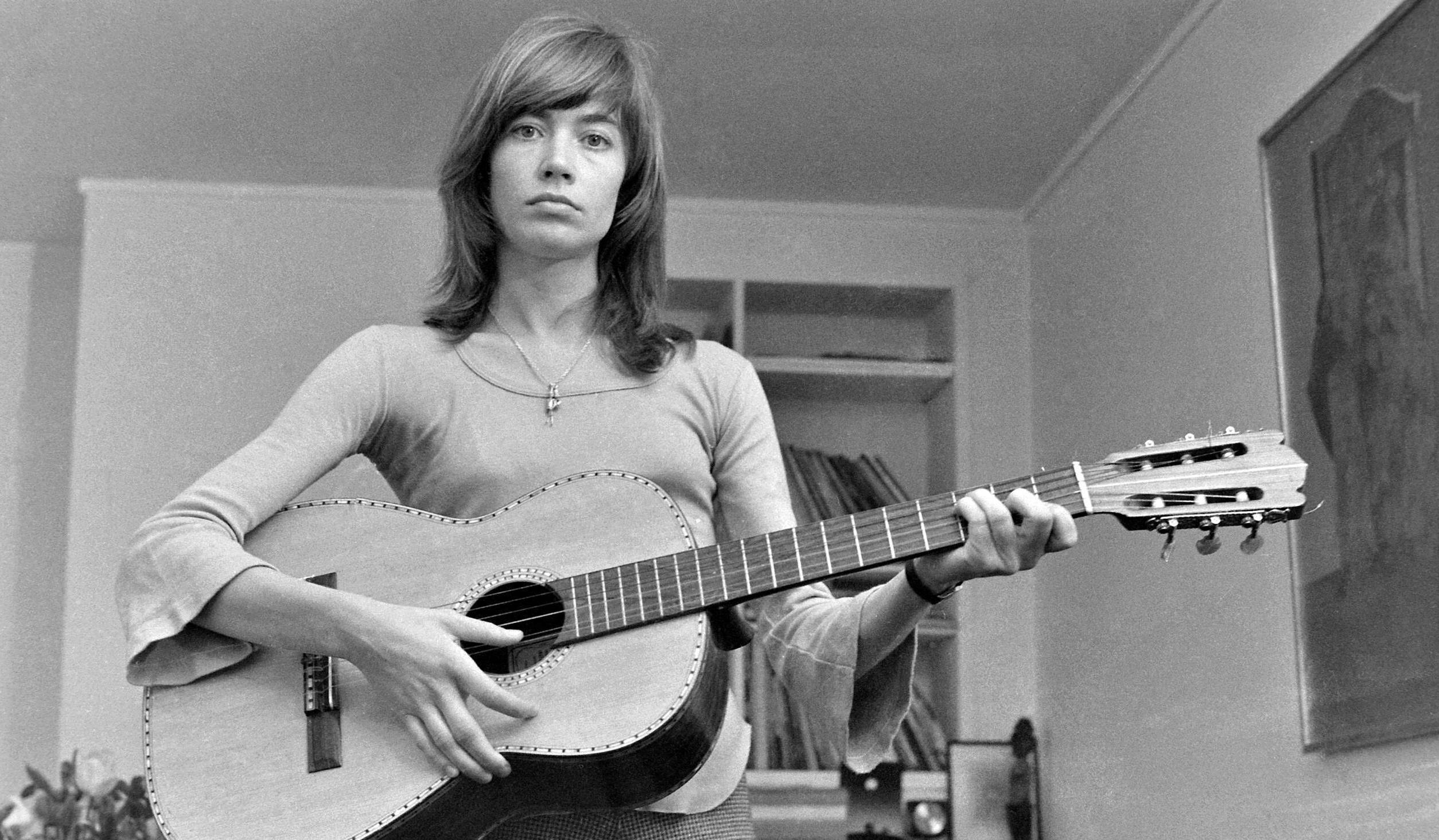 French singer, songwriter and actress Francoise Hardy holds a acoustic guitar as she poses at her apartment in Paris, Sept...