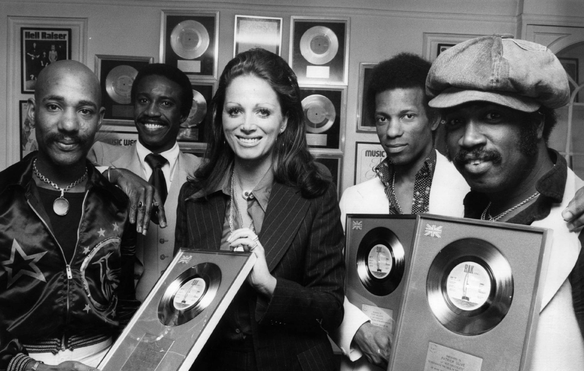 7th June 1974:  Author Jackie Collins presenting pop group Hot Chocolate with silver discs for the sales of their single '...
