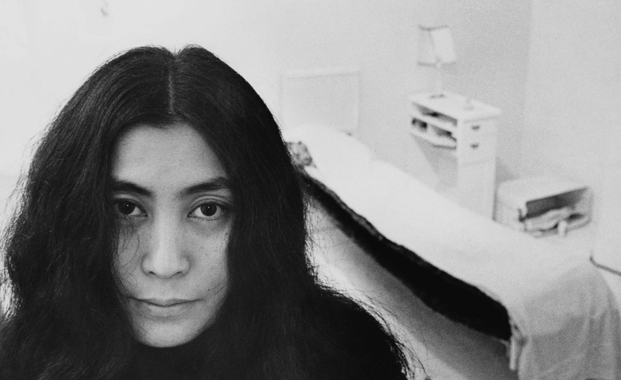Japanese artist and musician Yoko Ono sits in a white-painted half bedroom entitled 'Half-a-Room', part of her recent avan...