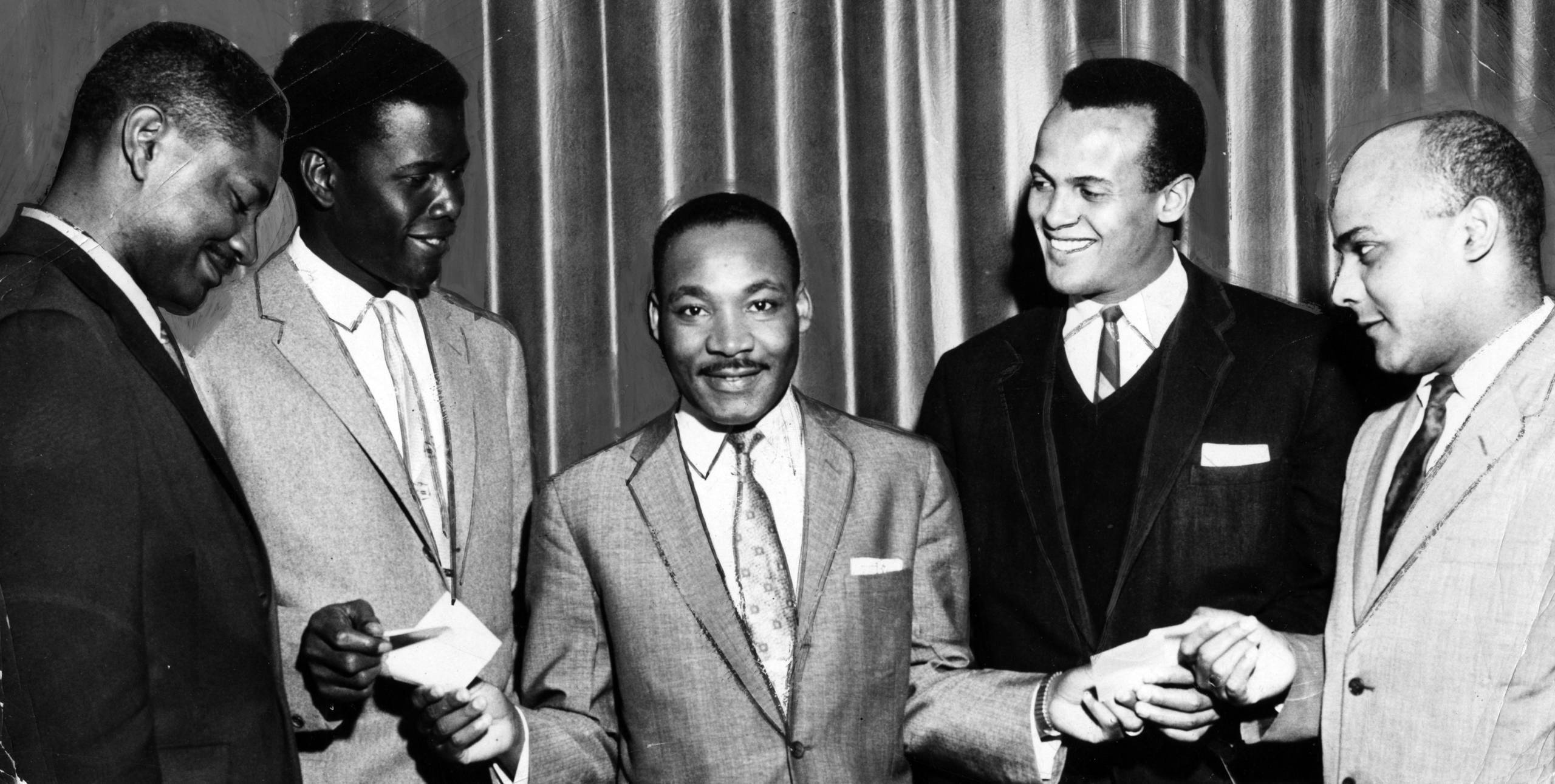 American Civil Rights and religious leader Dr Martin Luther King Jr (1929 - 1968) (center) smiles as he hands papers  to a...