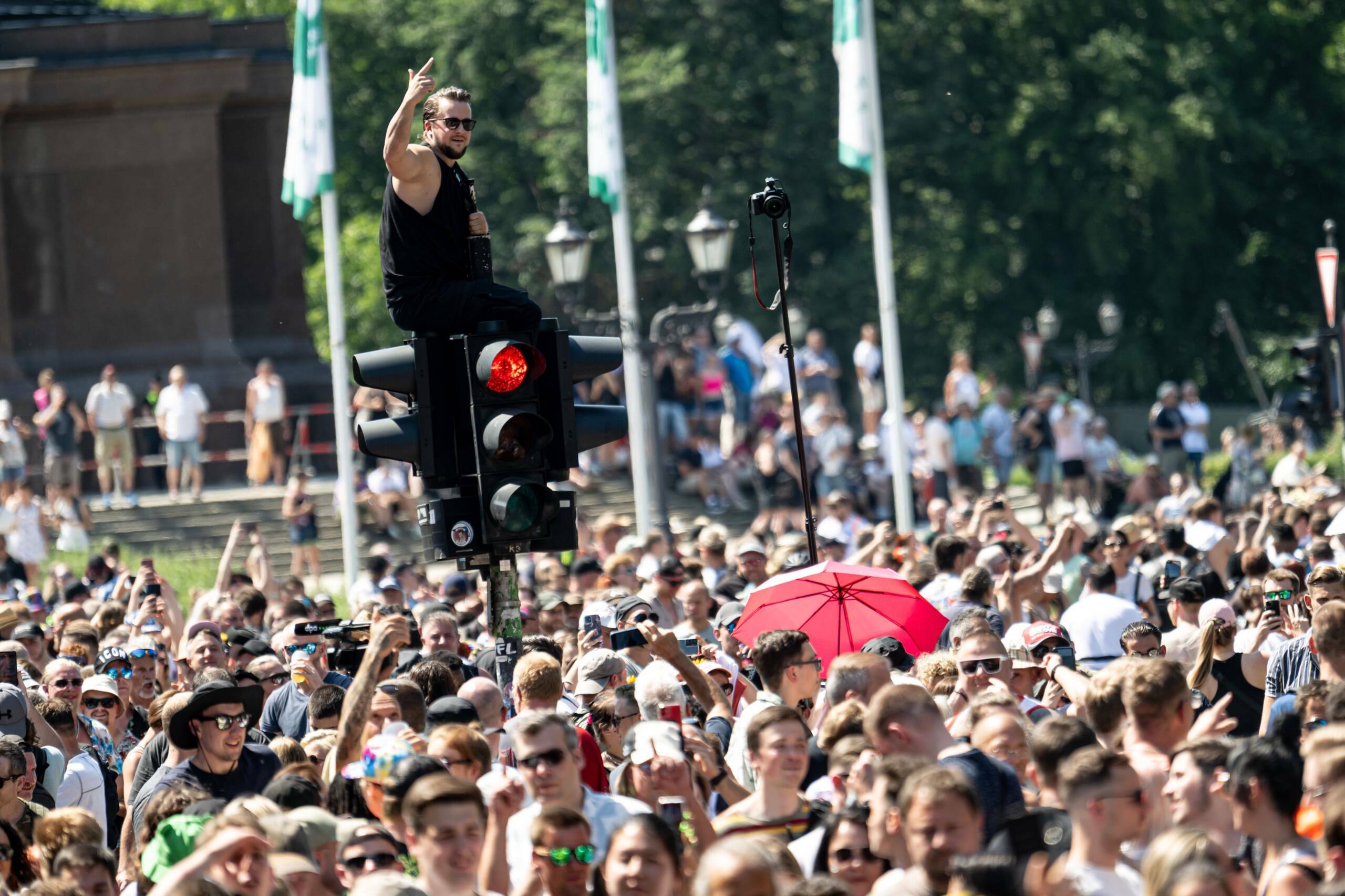 Eine Person ist auf der "Rave the Planet"-Technoparade auf der Straße des 17 Juni vor der Siegessäule auf eine Ampel gek...