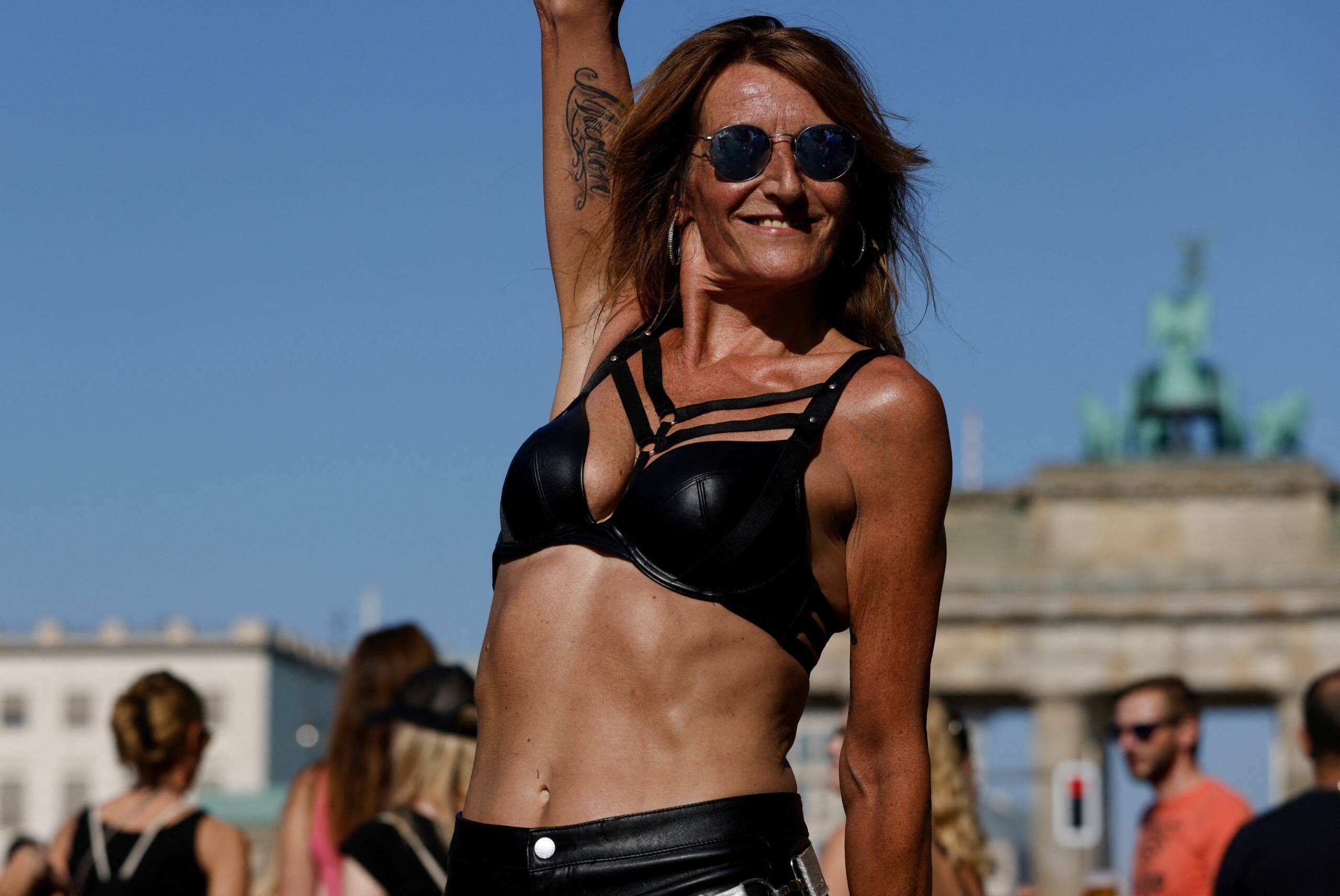 People dance as they pass the capital's landmark Brandenburg Gate with the TV Tower in the background during the "Rave the...