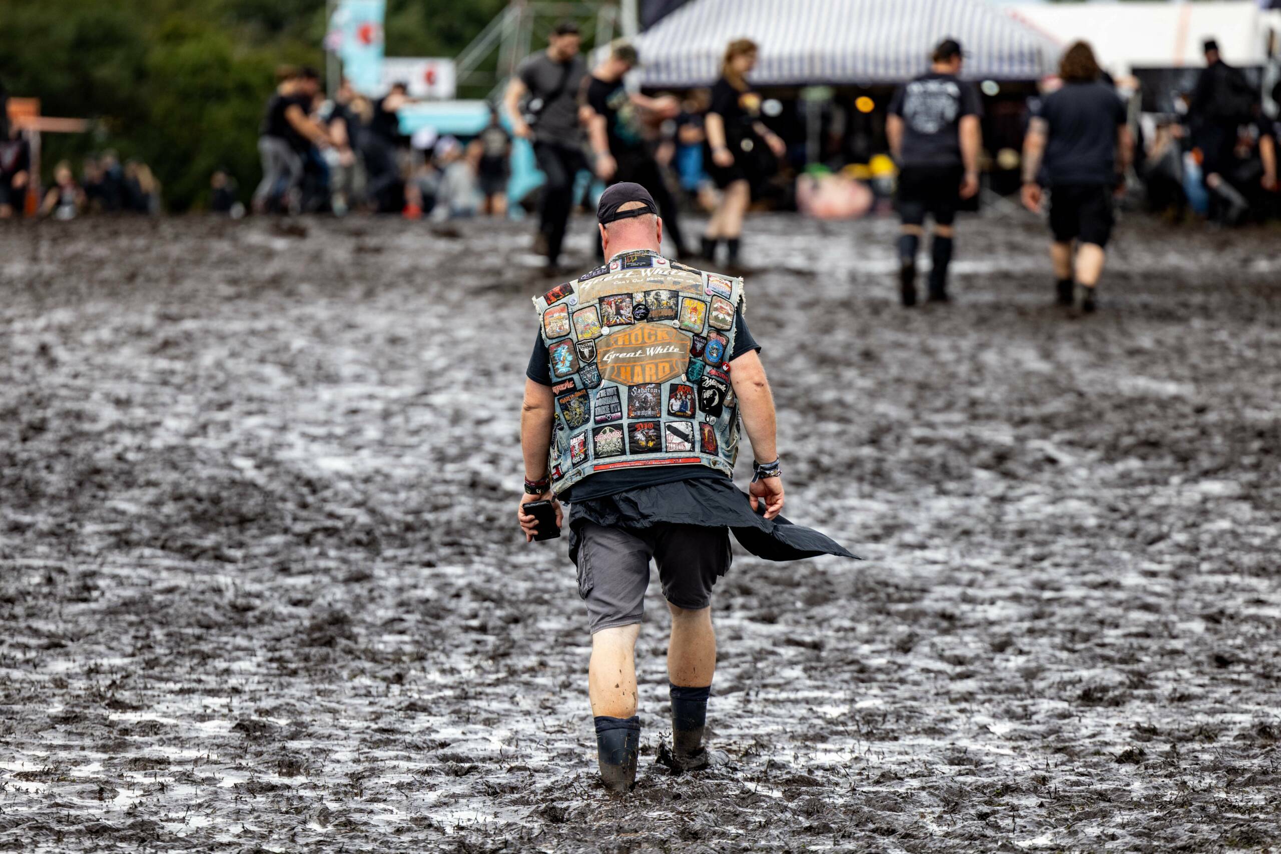 A visitor walks through mud on the festival grounds of the Wacken Open Air music festival in Wacken, northern Germany on A...