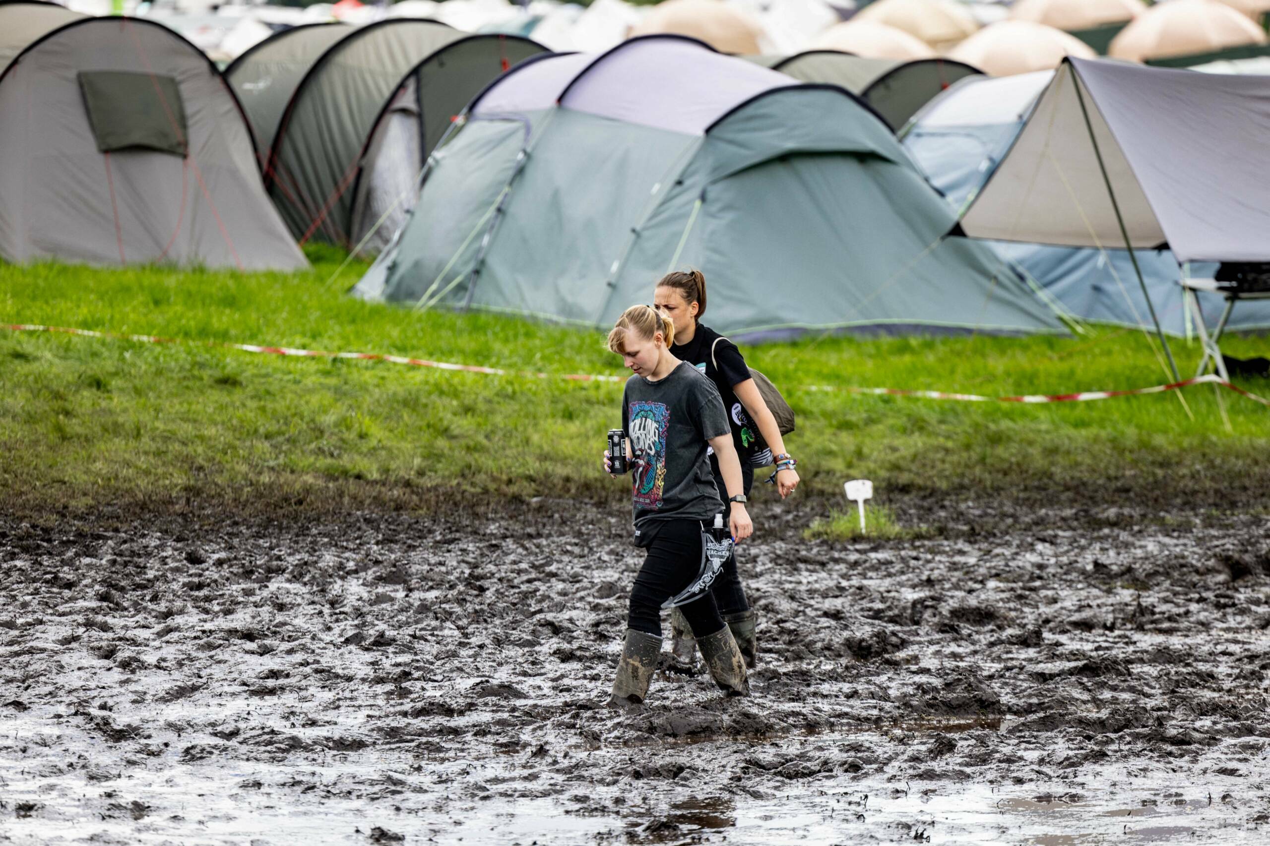 Festival-goers walk through mud past a camp site for the Wacken Open Air music festival in Wacken, northern Germany on Aug...