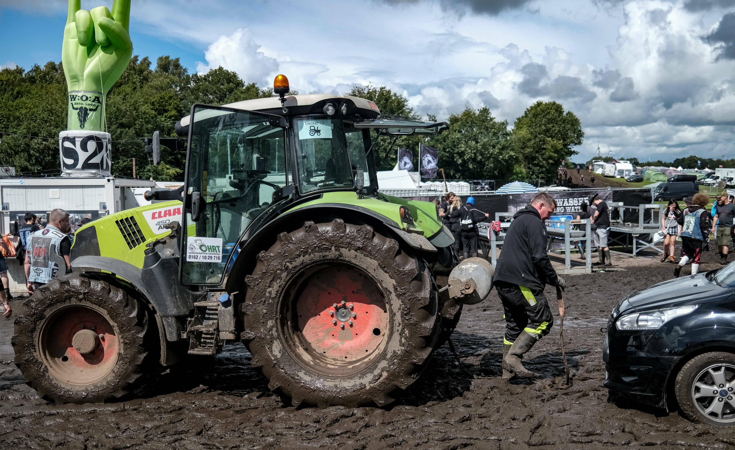 A tractor pulls a car to a parking lot on the muddy festival grounds ahead of the opening of the Wacken Open Air music fes...
