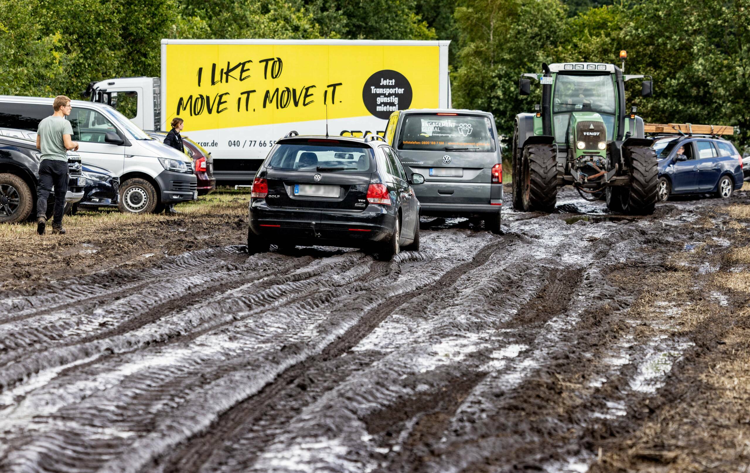 A tractor pulls a car to a parking lot on the muddy festival grounds ahead of the opening of the Wacken Open Air music fes...