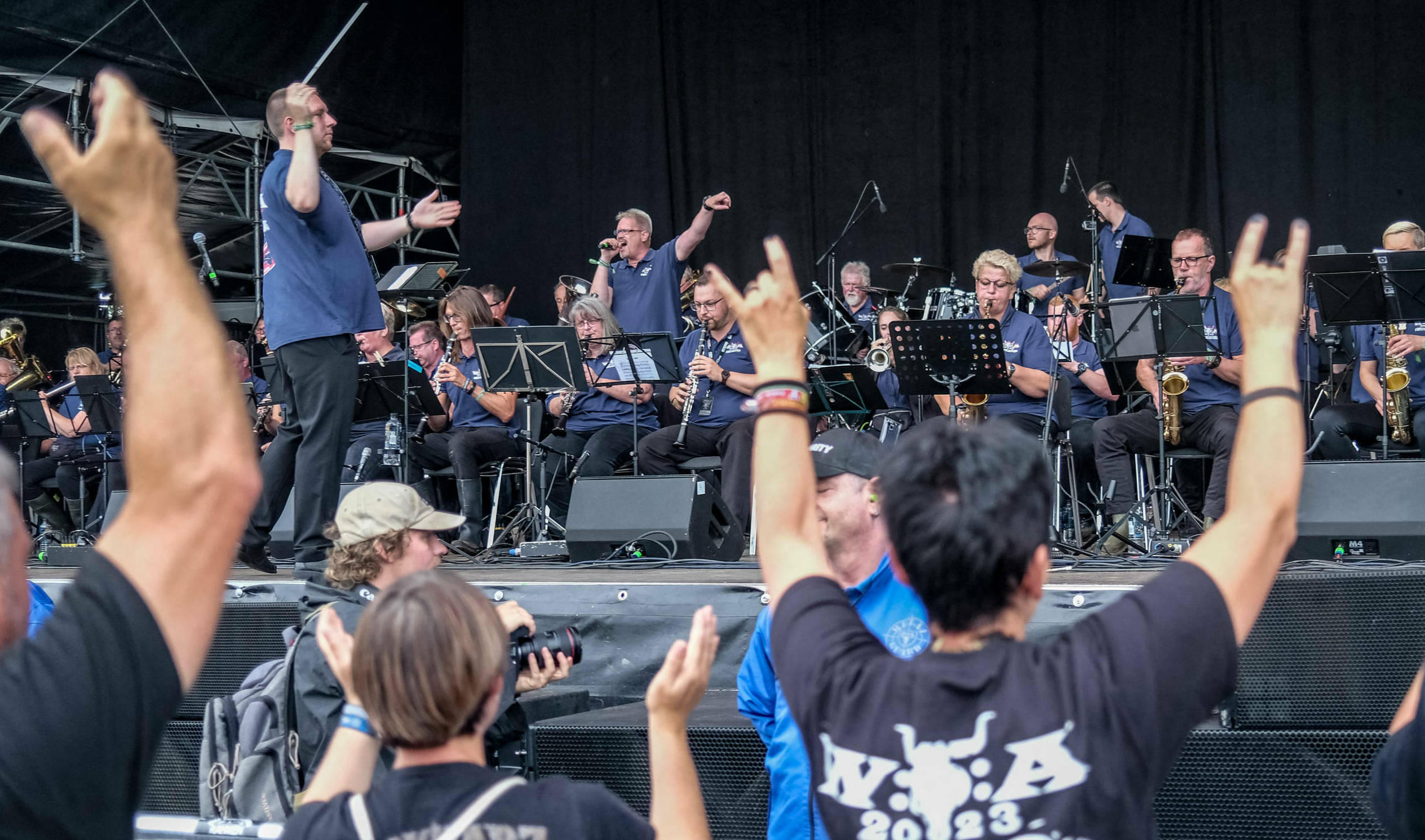 A festival-goer (R) shows the sign of the horns hand gesture as the Wacken Firefighters' brass band opens the Wacken Open ...