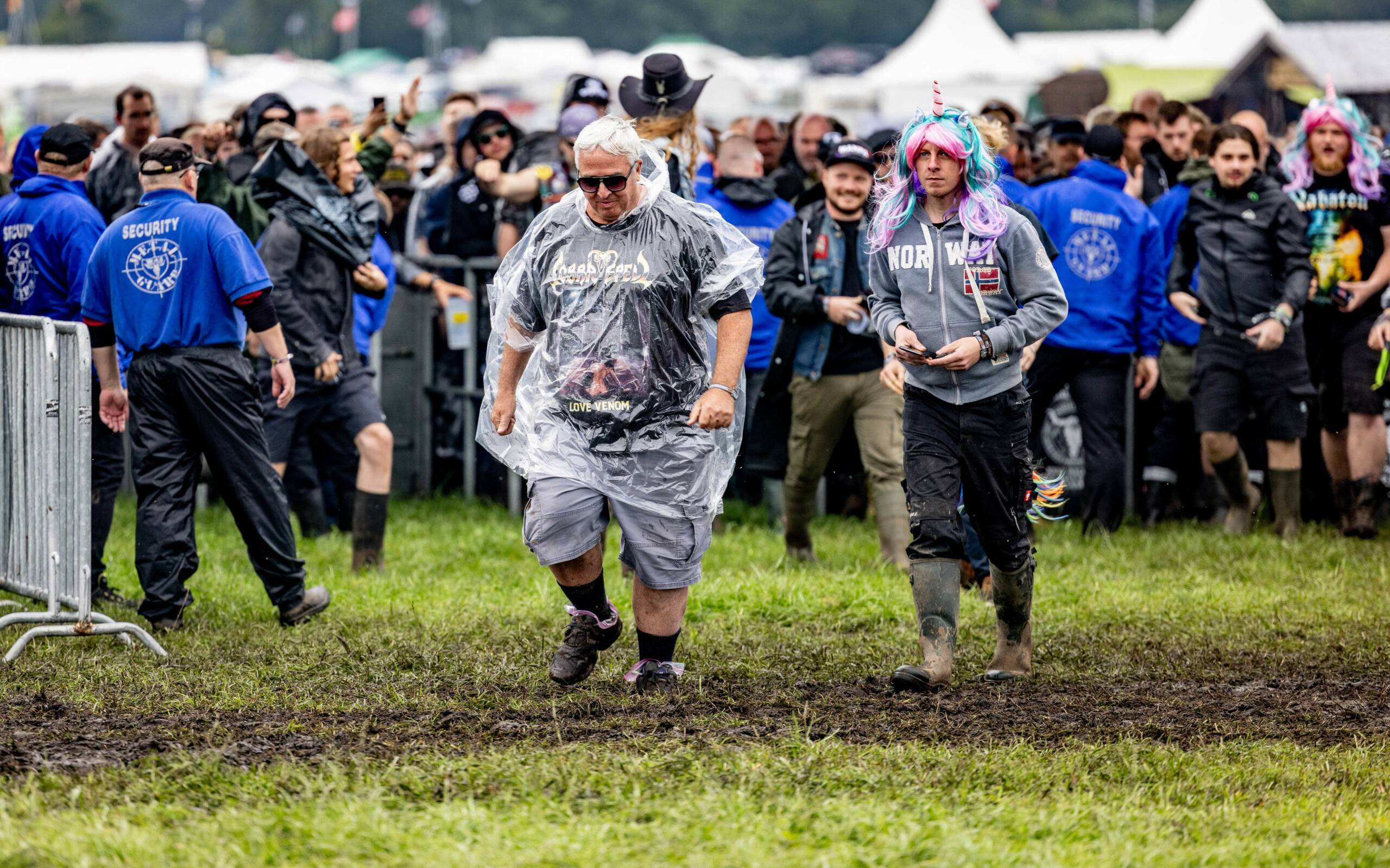 Festival-goers walk through the mud as they enter the grounds of the Wacken Open Air music festival on August 2, 2023 in W...