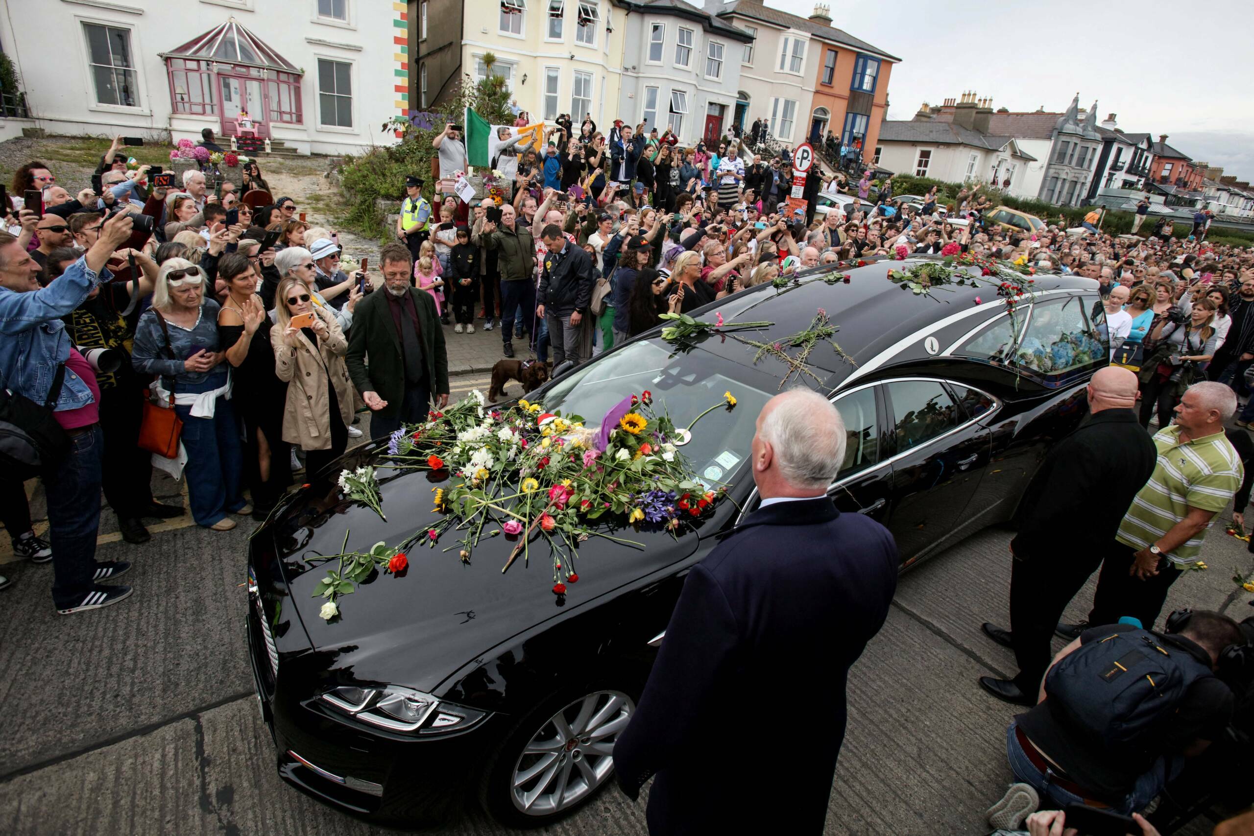 TOPSHOT - People lay flowers and tributes on the hearse during the funeral procession of late Irish singer Sinead O'Connor...