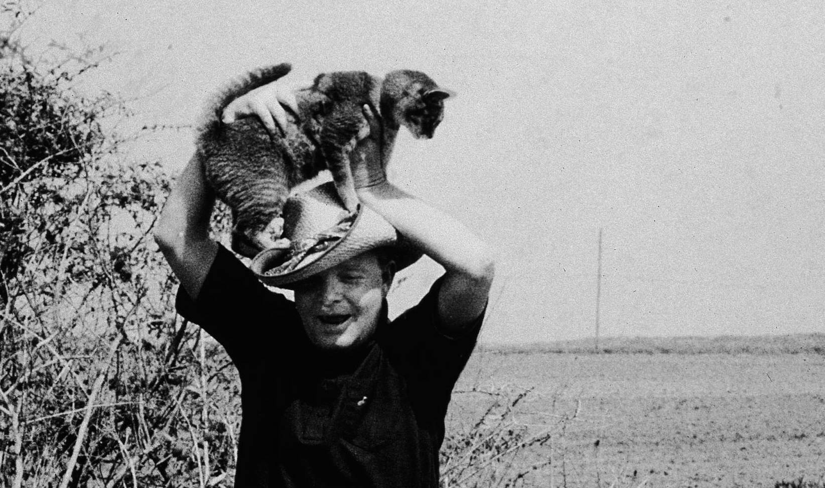 American author Truman Capote (1924 - 1984) smiles while playing with his  pet cat and dog in Sagaponack, Long Island, New...