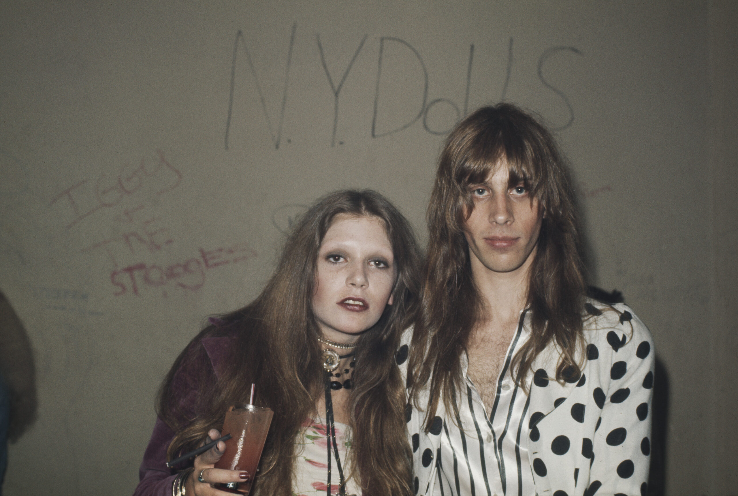 Club goers in front of graffiti reading 'NY Dolls' and 'Iggy and the Stooges' at Whisky a Go Go, a nightclub in West Holly...