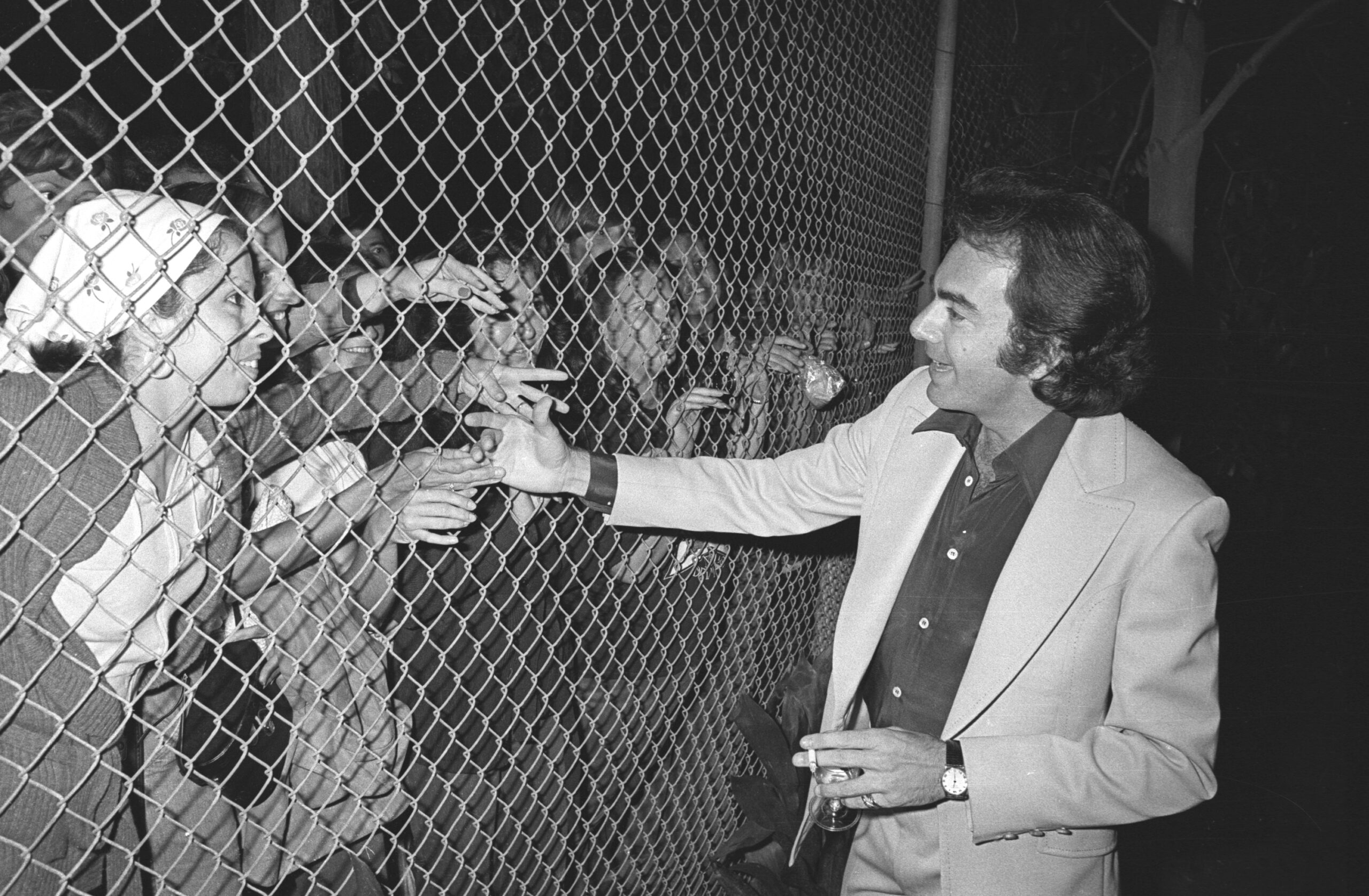 LOS ANGELES - CIRCA 1977:  Singer Neil Diamond signs autographs for fans on the other side of a chain link fence in in cir...