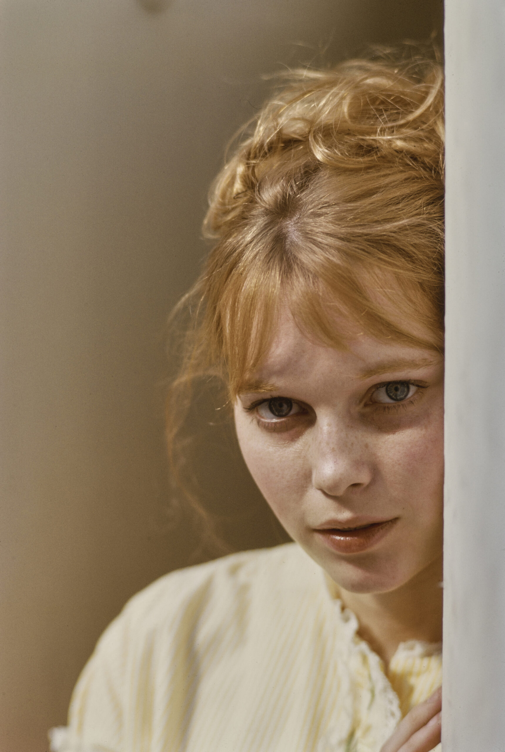 American actress Mia Farrow wearing a yellow-and-white striped outfit with a lace-trimmed neckline, in a studio portrait, ...