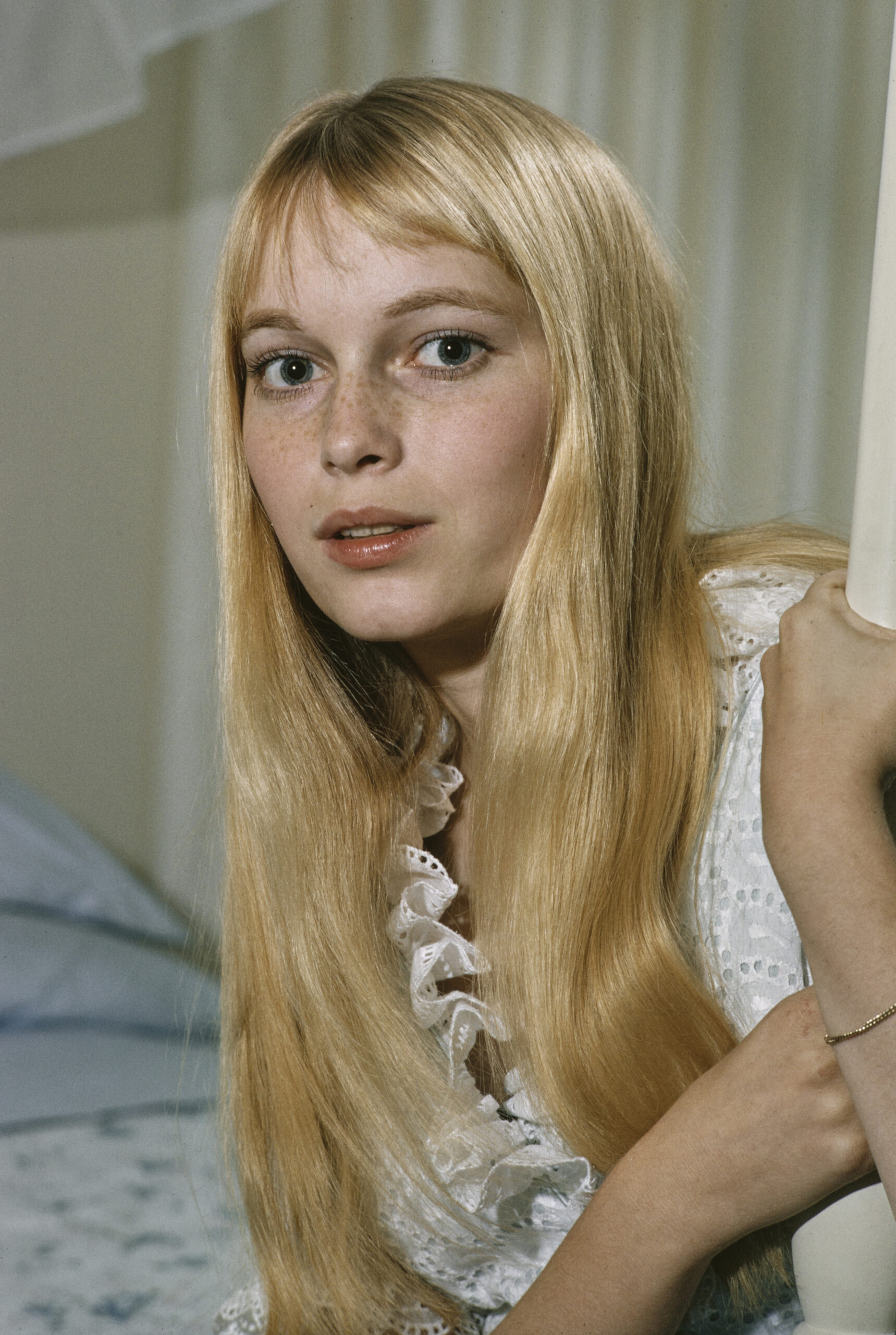 American actress Mia Farrow wearing a white-and-grey patterned sleeveless outfit with a ruffled neckline, in a studio port...