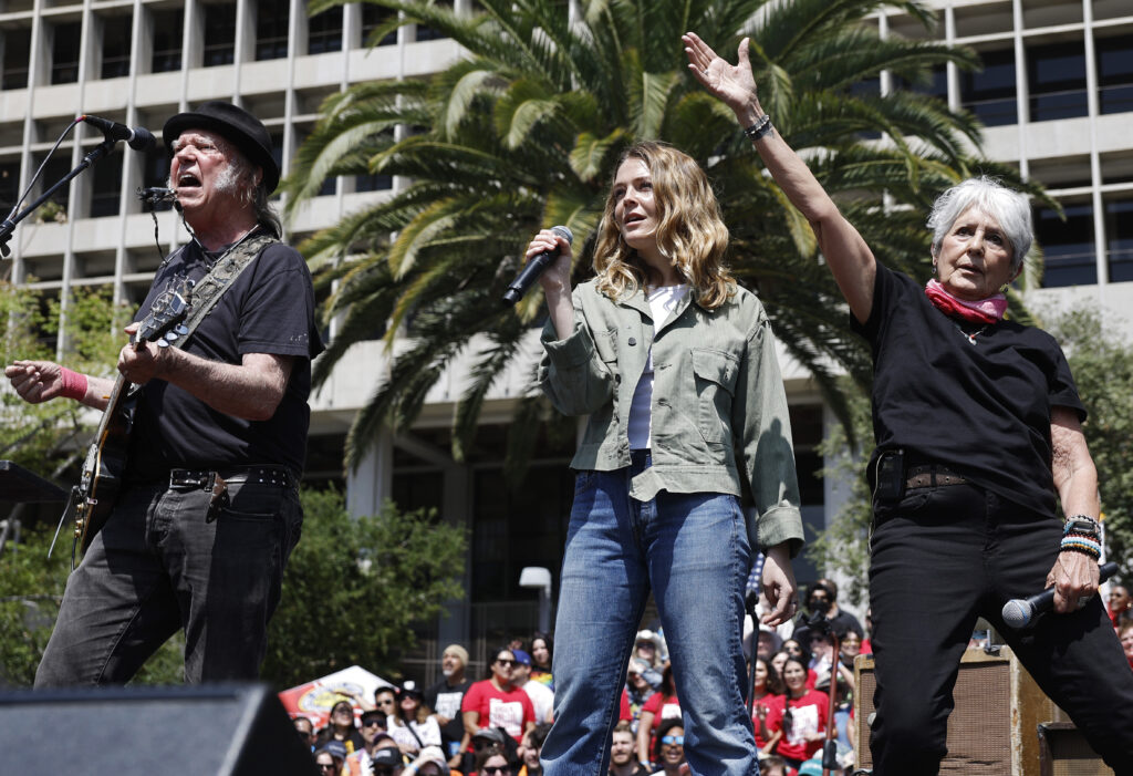 LOS ANGELES, CALIFORNIA - APRIL 12: (L to R) Neil Young, Maggie Rogers and Joan Baez perform during the ‘Fighting Oligar...