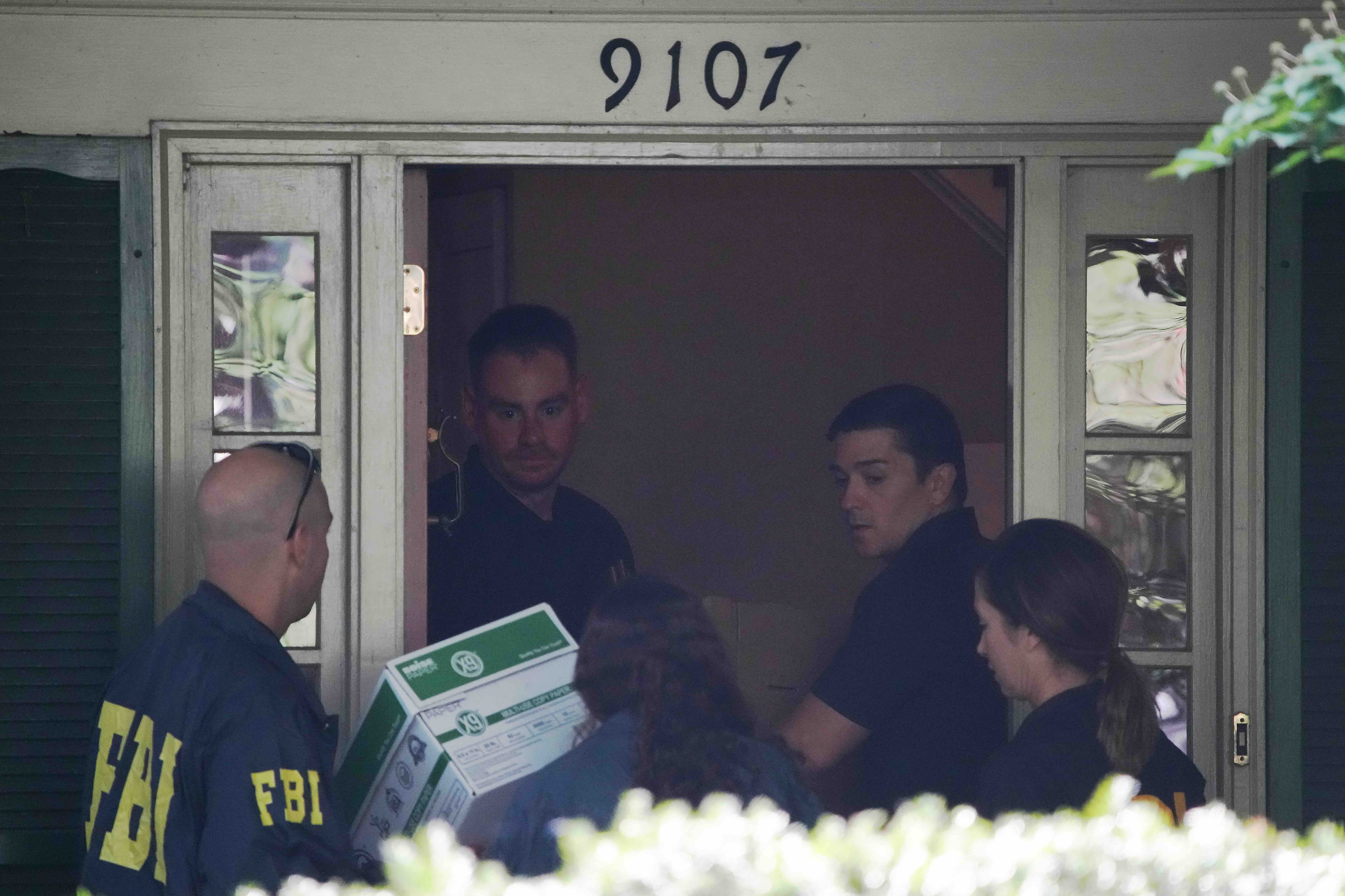 BETHESDA, MARYLAND - AUGUST 22: FBI agents carry boxes at the home of John Bolton, former national security adviser to Pre...
