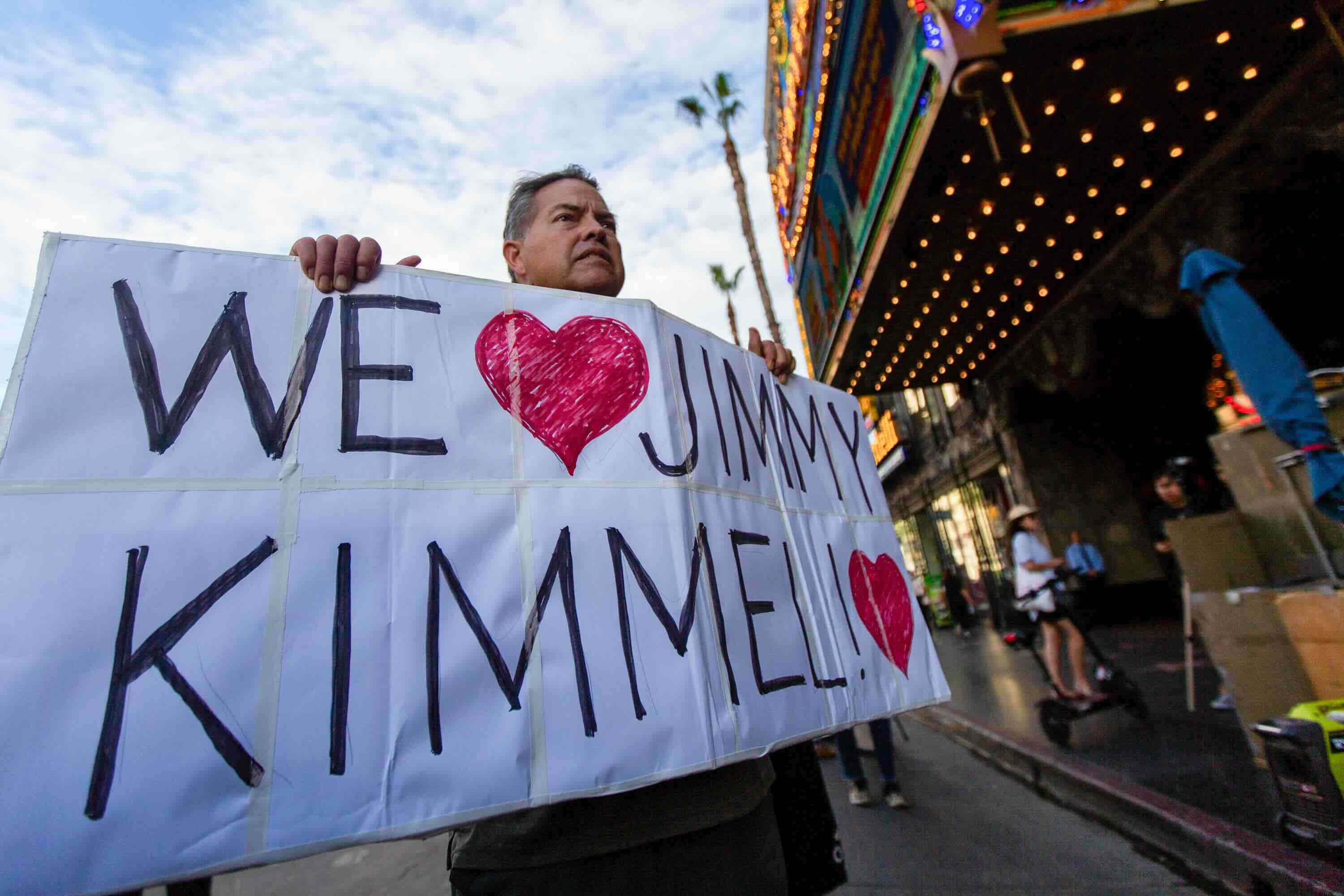 A man holds a sign during a protest against ABC removing Jimmy Kimmel Live! off the air in front of the El Capitan Theatre...