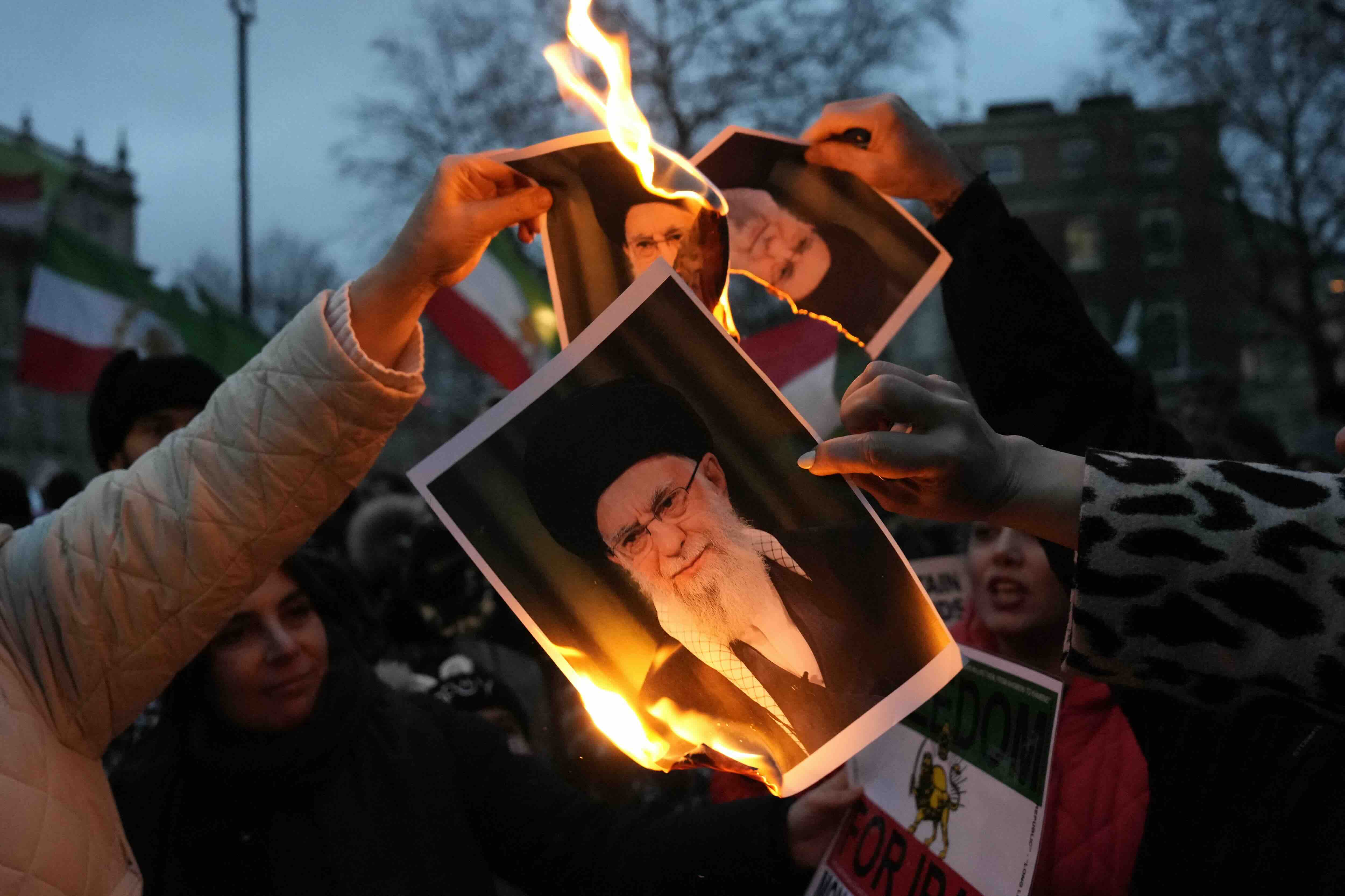 Protestors burn images of Ayatollah Ali Khamenei during a rally held in Solidarity with Iran's Uprising, organised by The ...