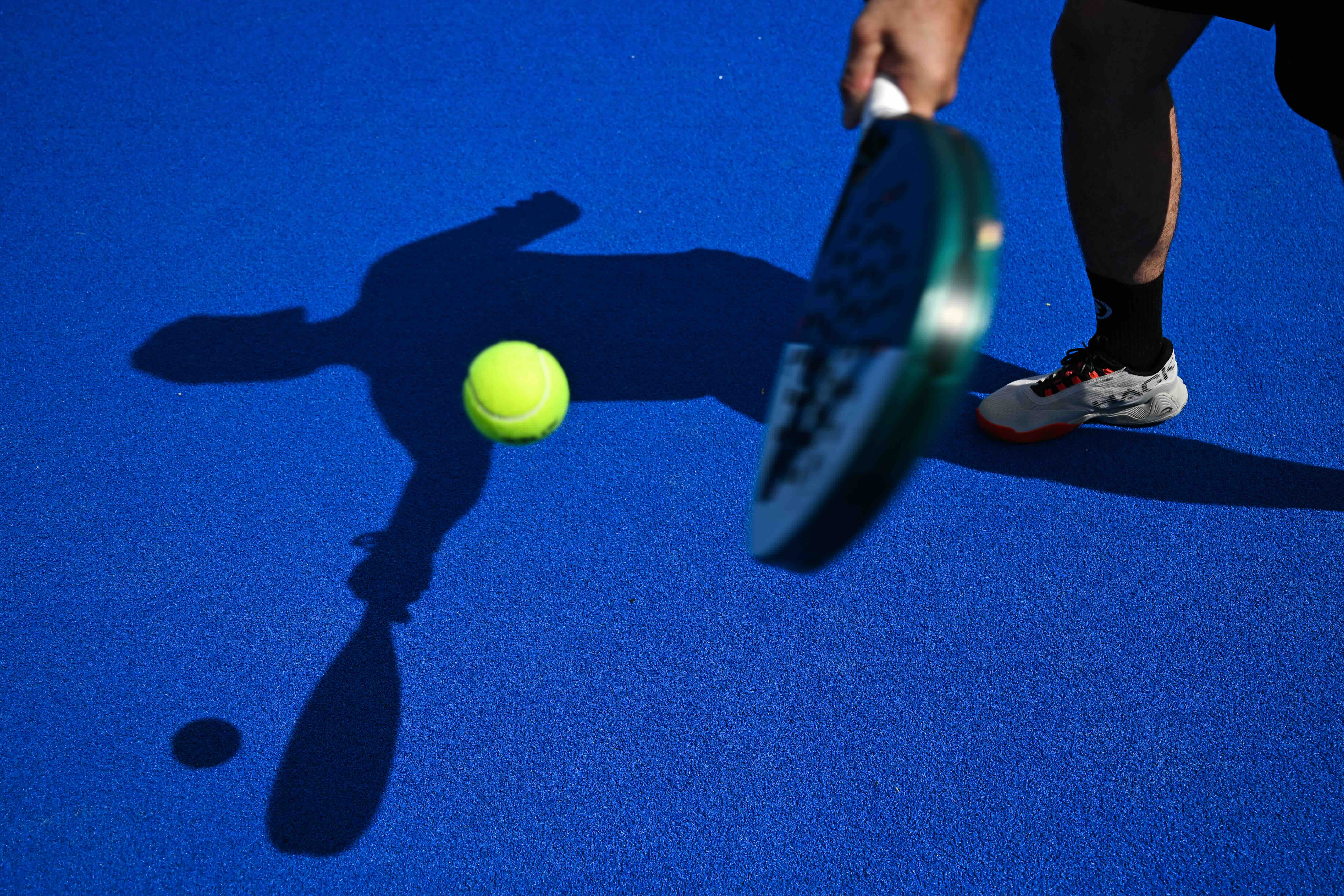 A padel tennis player is silhouetted at the Beziers Indoor Padel club in Beziers, southern France on July 22, 2025. The pa...