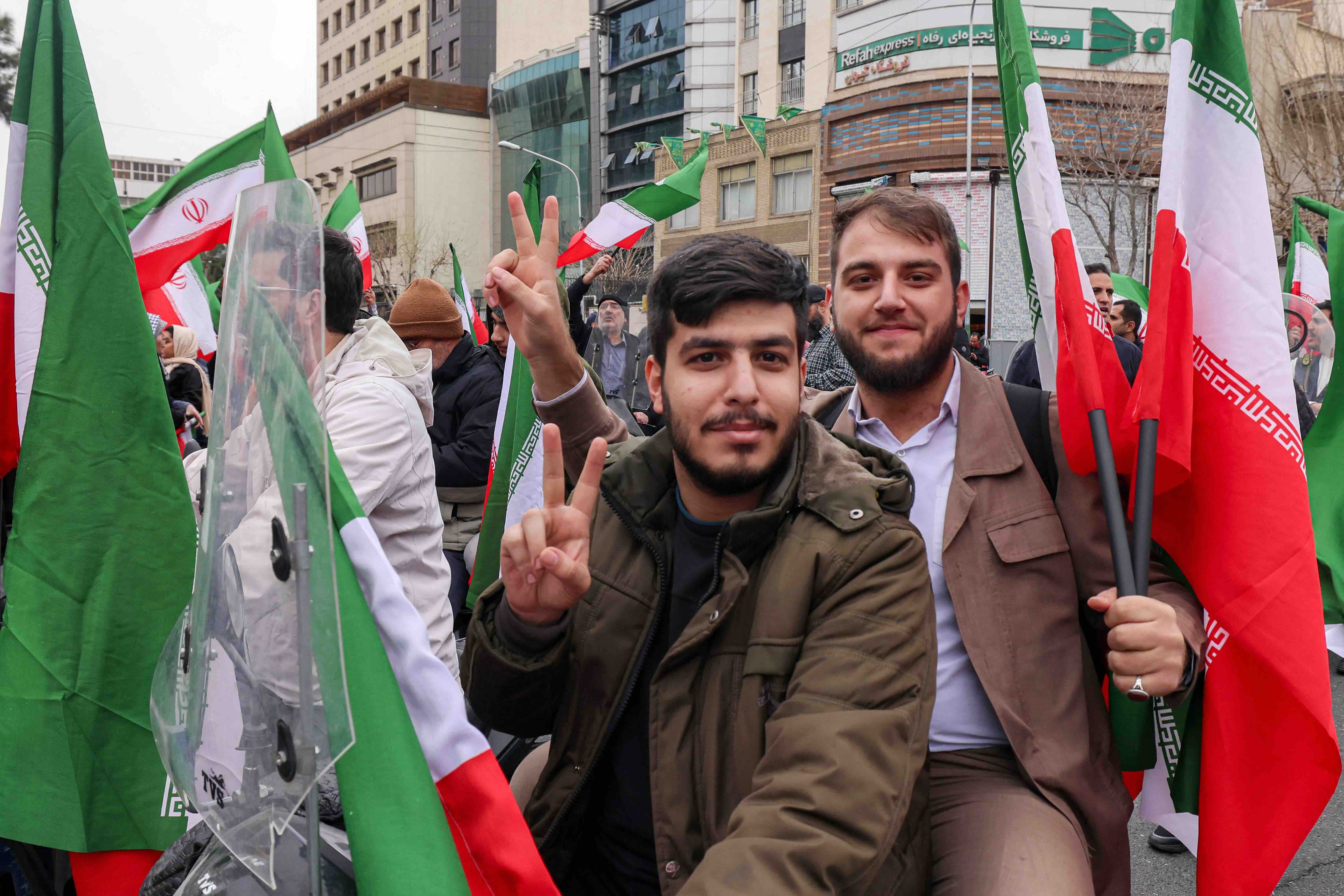 Men pose with Iranian national flags during a demonstration in support of the government and against US and Israeli strike...