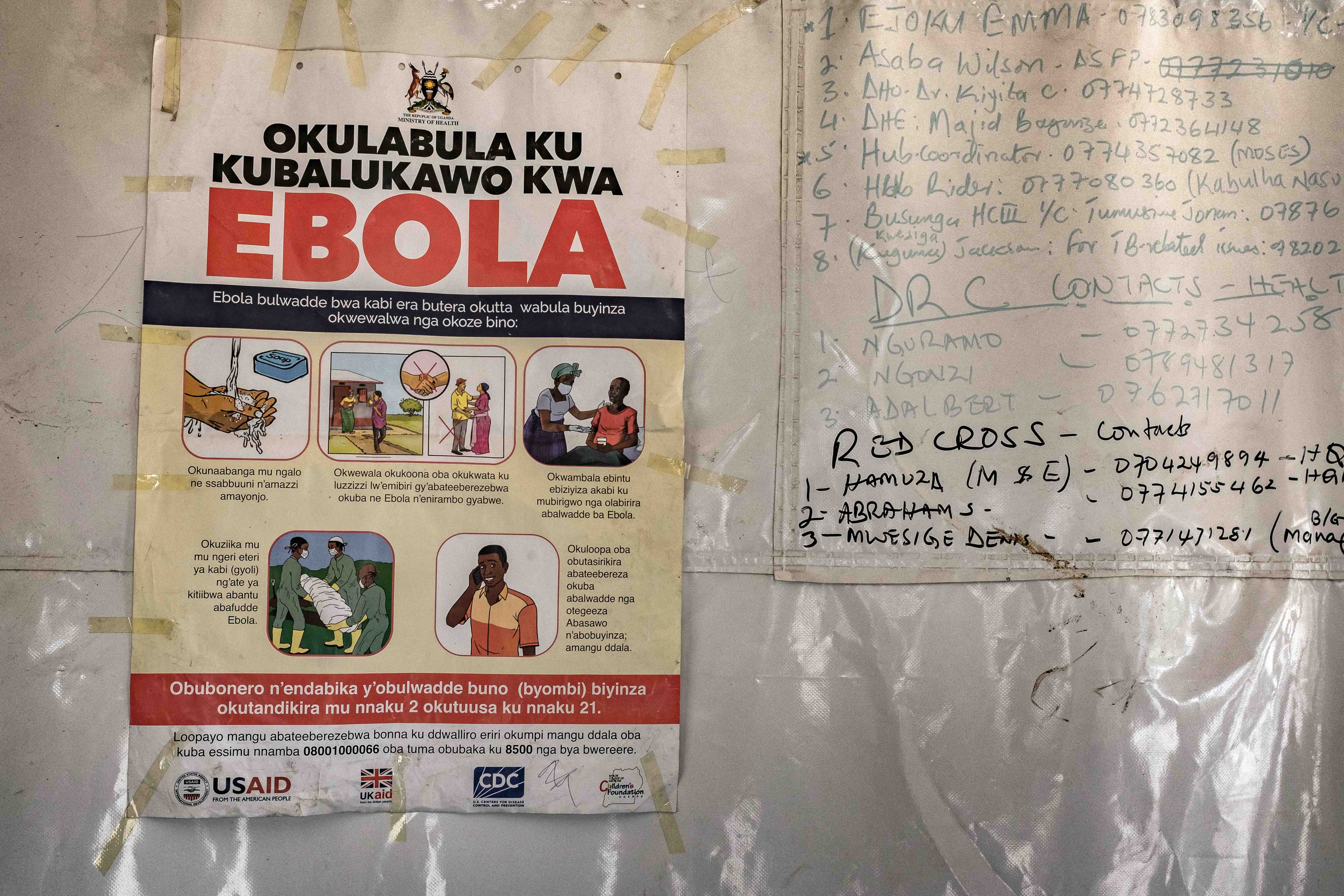 A poster displaying Ebola emergency contact numbers is pinned to a tent at the Busunga border crossing between Uganda and ...